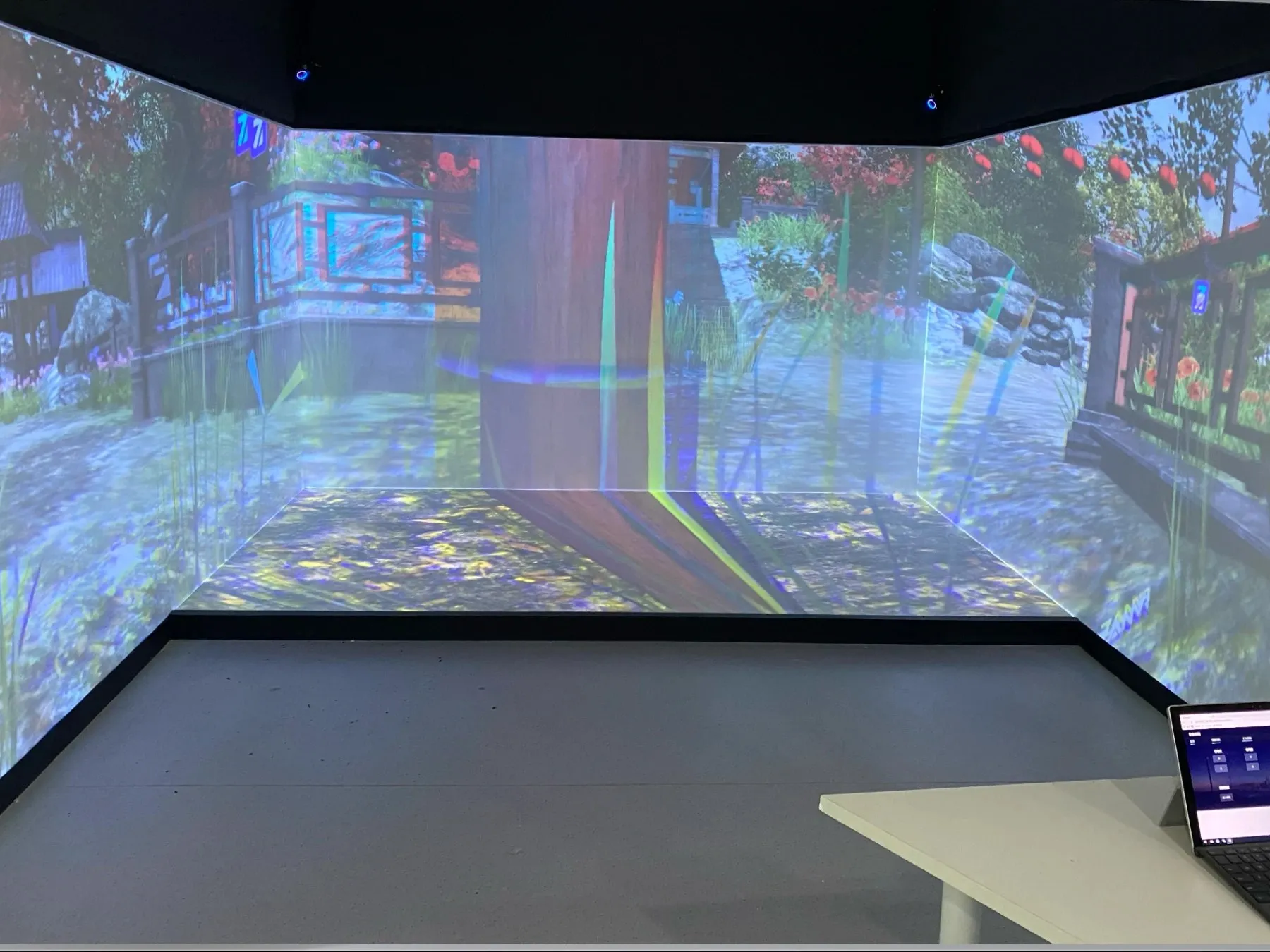 An AeduVerse scene projected across the walls and floor of a CAVE, run from a laptop