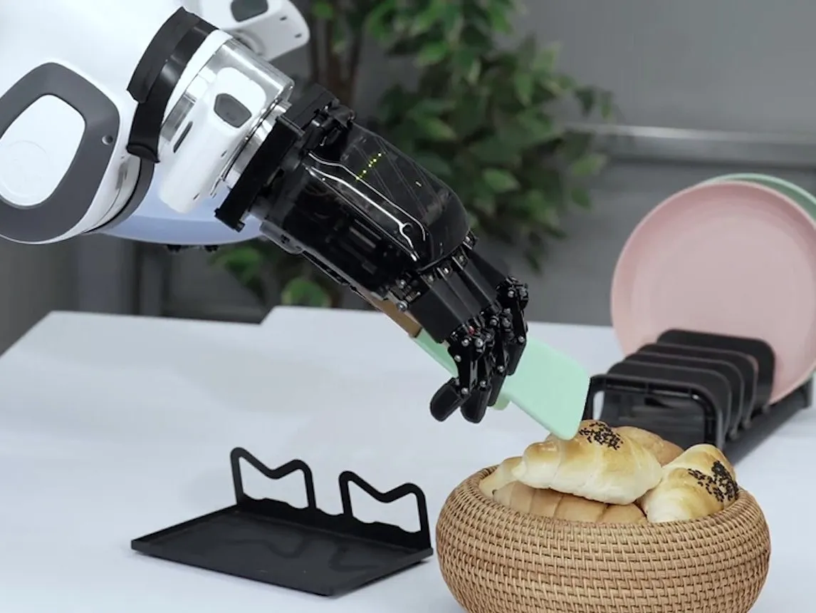 A robot arm with a dexterous hand holding a spatula over a bread basket