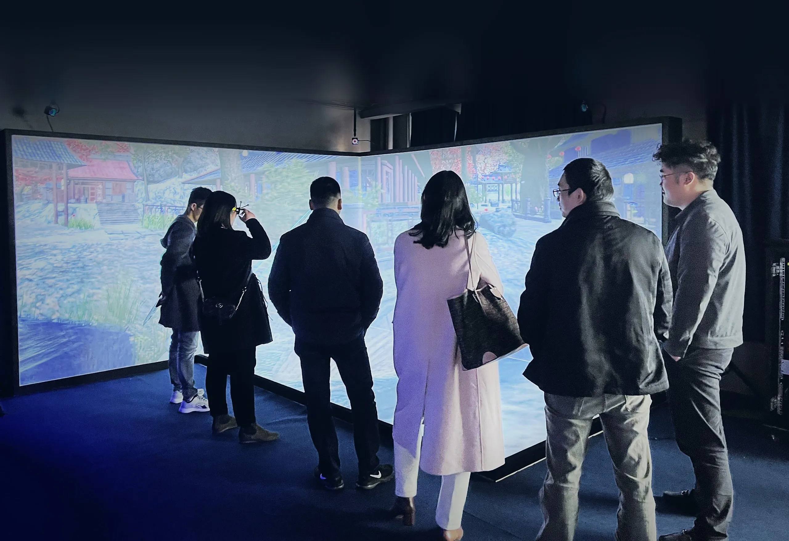 A group of visitors, some in 3D glasses, in front of a three-wall CAVE showing a garden scene